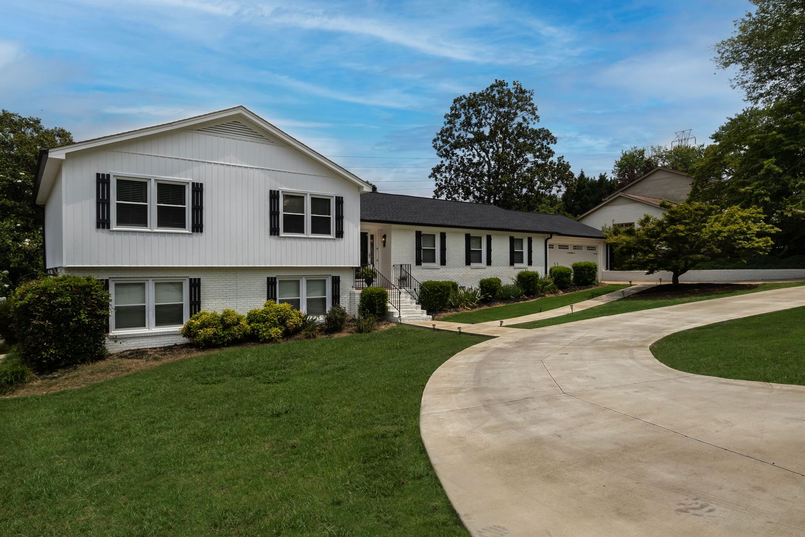Wide curving concrete driveway sweeping up to a two-car garage at a suburban home