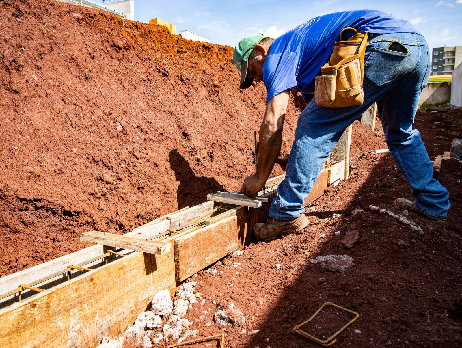 Worker setting and bracing timber forms with steel in place ahead of a concrete pour