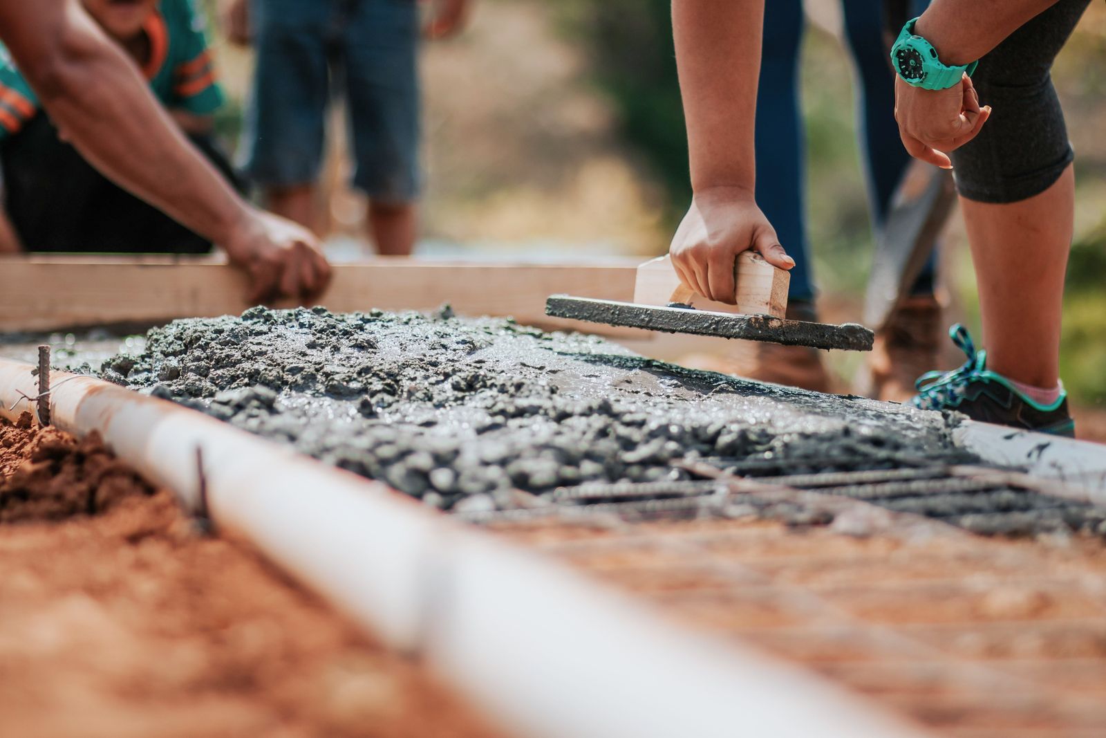 Concrete crew hand-floating a freshly poured slab inside timber forms over rebar