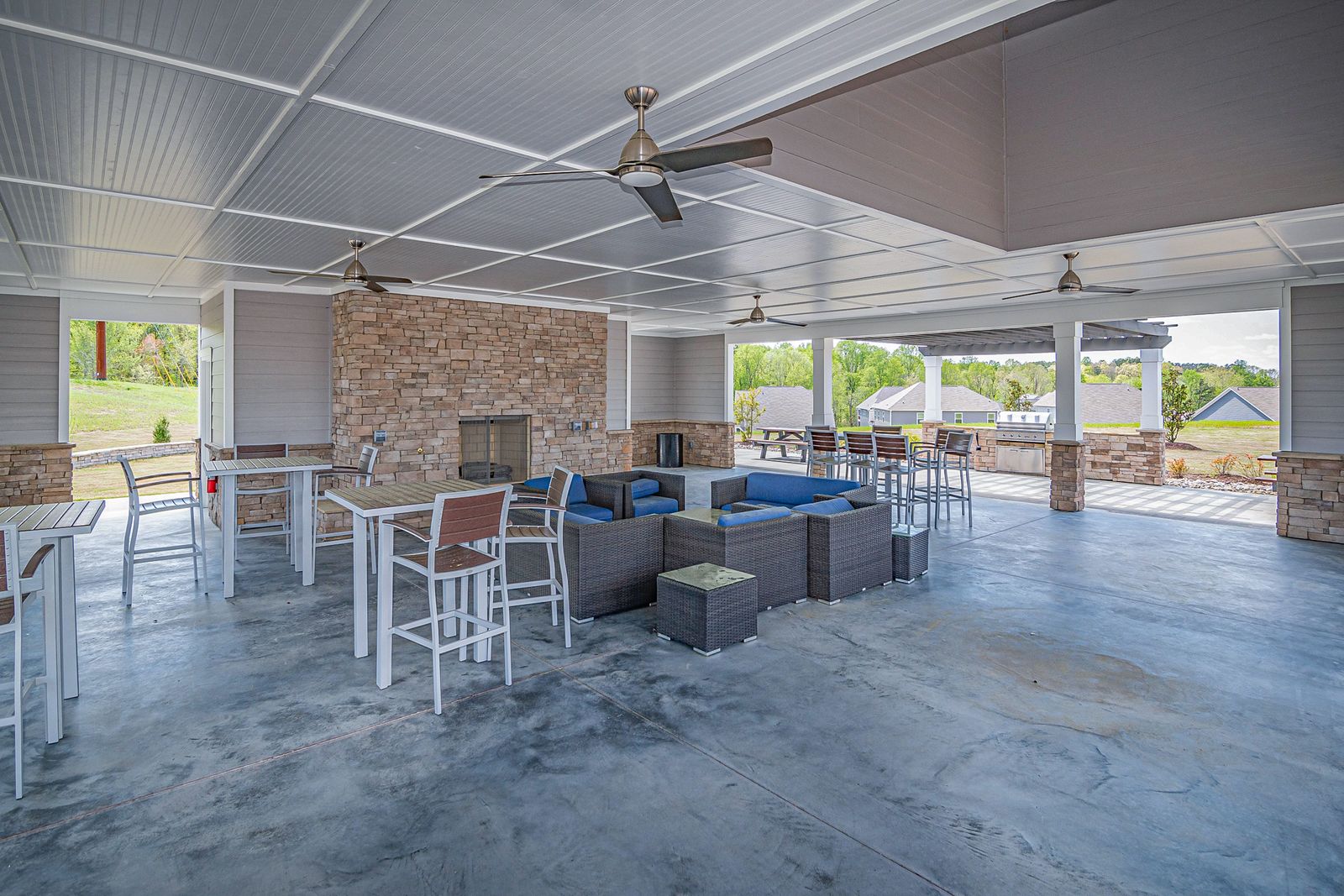 Large finished concrete slab under a covered patio with seating and a stone fireplace