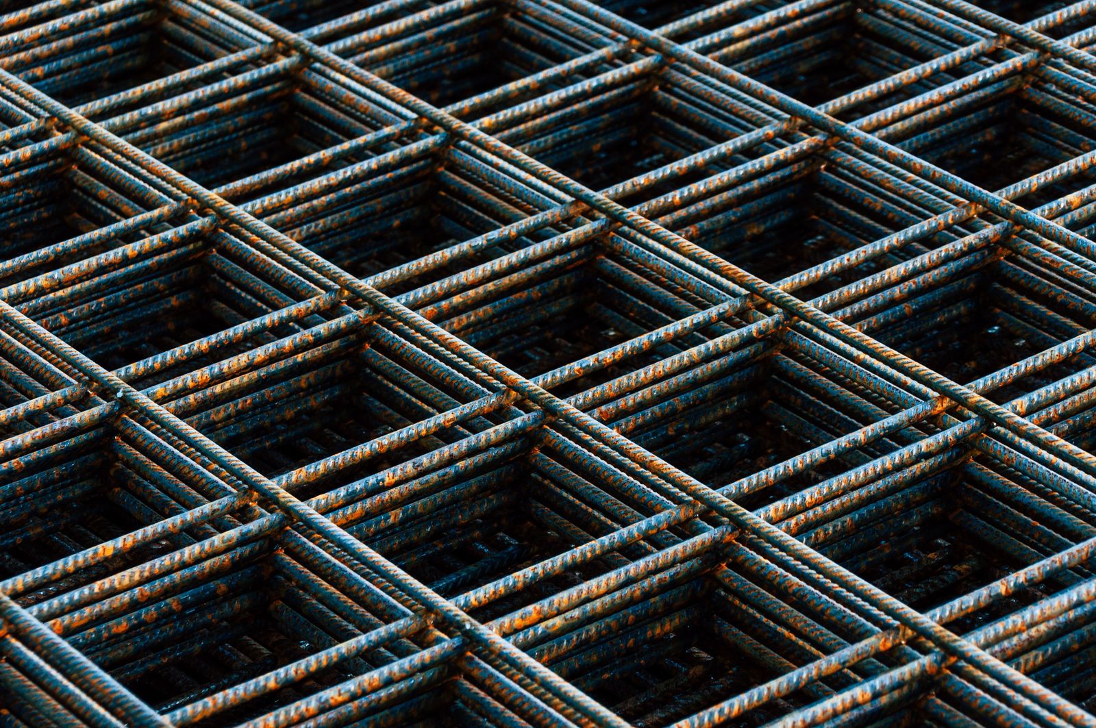 Stacked sheets of rusted reinforcing mesh waiting to be tied into a slab