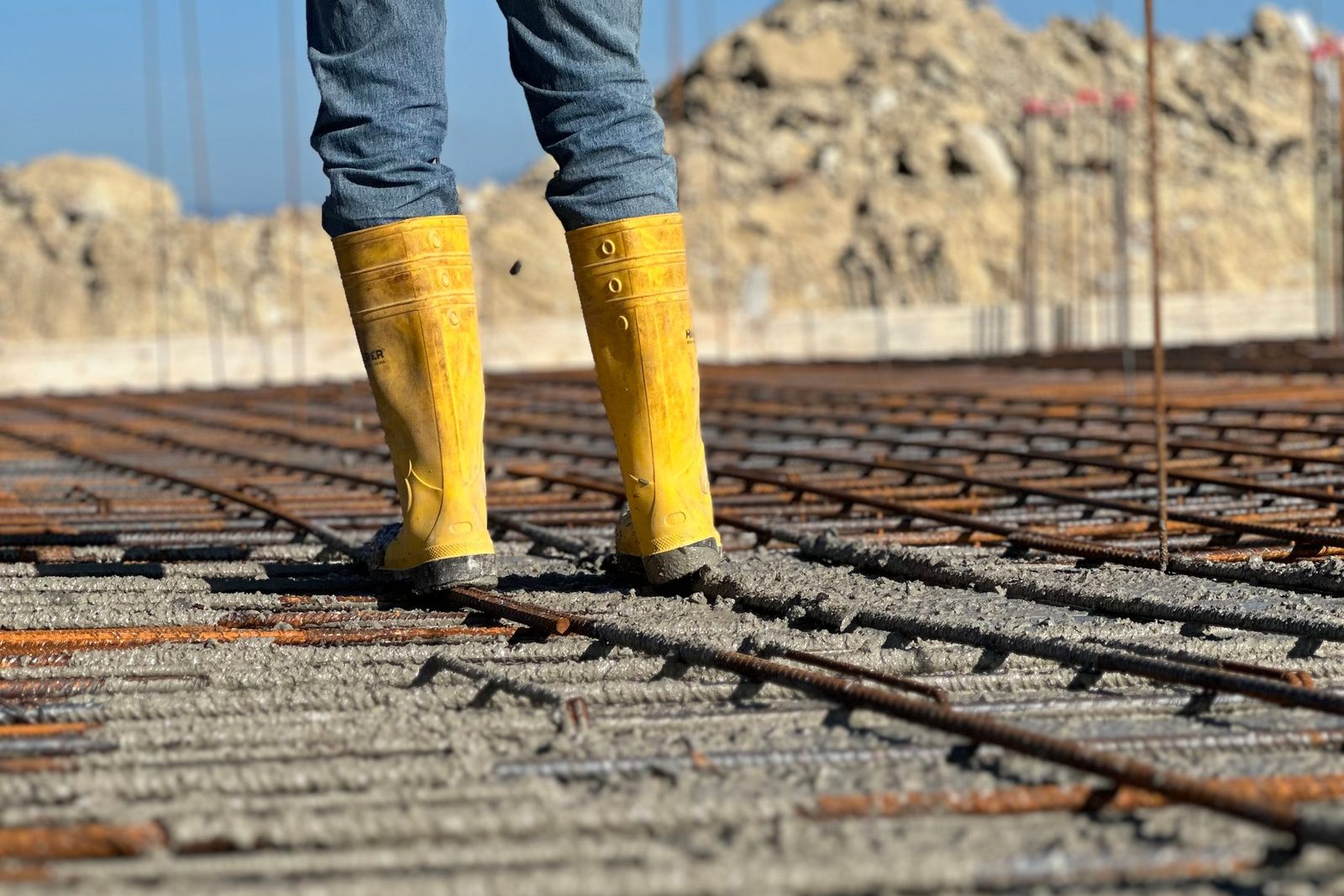 Worker standing on a tied rebar mat laid out over a prepared slab base before the pour
